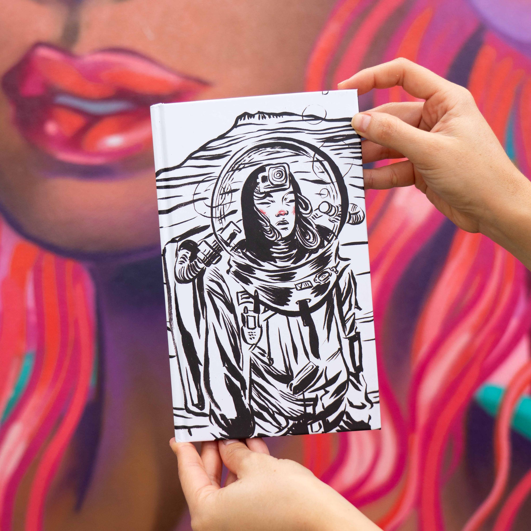 Person holding a black and white illustration of an astronaut on a colorful background