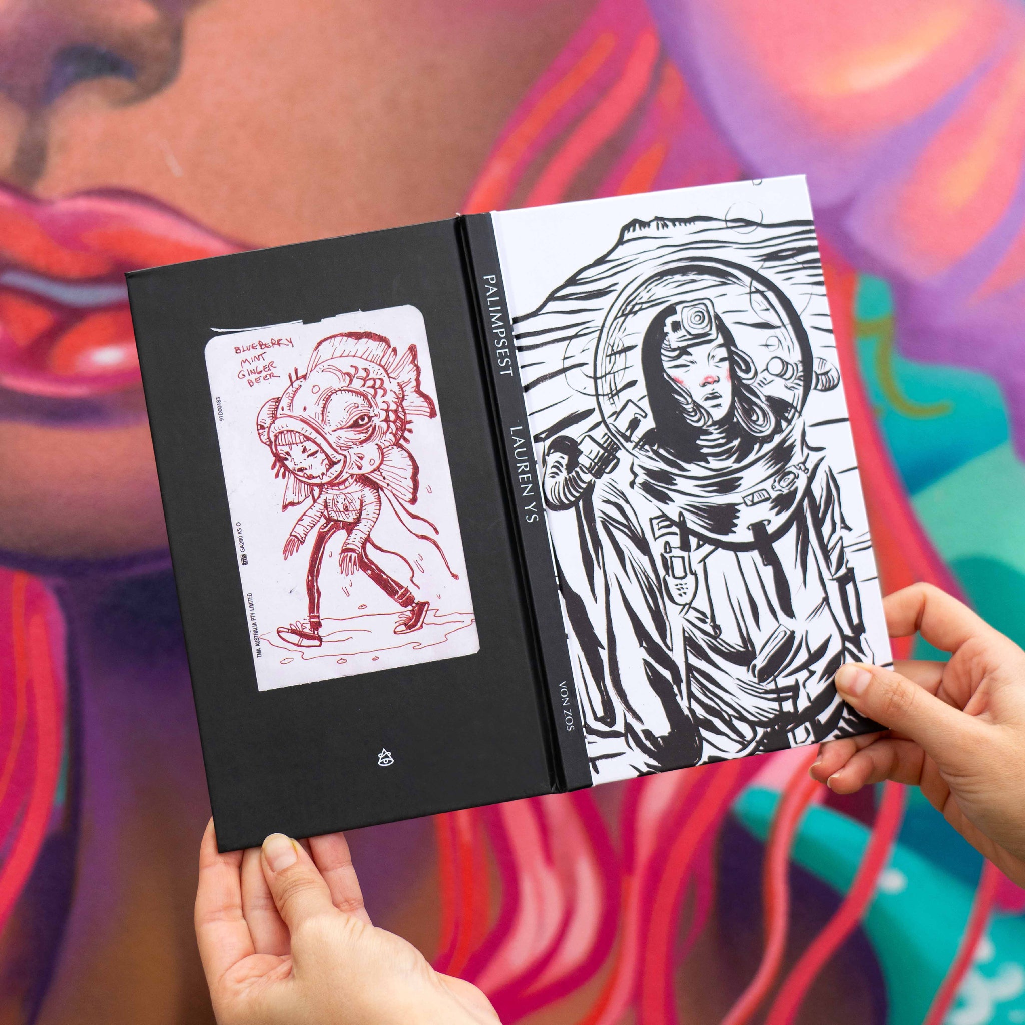Open book with black and white illustrations held by hands against a colorful background